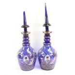 A pair of gilded blue glass Ottoman style large decanters, with portrait panels, largest height 57cm