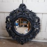 A large ornate black painted foliate circular bevel-edge wall mirror, overall 100cm x 82cm