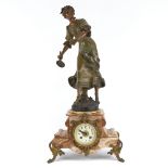 A French coloured marble-cased mantel clock, circa 1910, surmounted by a figure of a lady tennis