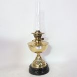 A Vintage embossed brass oil lamp on black ceramic base, with glass chimney, height to fitting 32cm