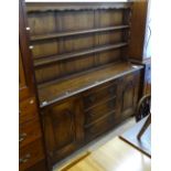 A modern oak dresser, with open plate rack, drawers and fielded cupboards under, on stile legs,