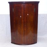 An 18th century crossbanded mahogany bow-front hanging corner cupboard, W72cm, H105cm