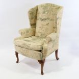 A Georgian style upholstered wing armchair, with Oriental design upholstery on cabriole legs, modern
