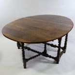 A large 18th century solid oak oval gateleg dining table, with barley twist supports and stretchers,