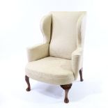 A 19th century upholstered wing armchair on walnut cabriole legs