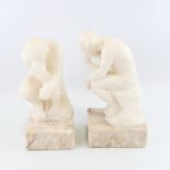 A pair of carved alabaster crouching figures on marble block plinths, height 29cm Good condition