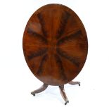 A 19th century oval mahogany tilt-top dining table, with segmented veneer top, on heavy carved