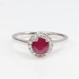 A modern 14ct white gold ruby and diamond cluster ring, set with round-cut ruby and round
