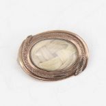 A small Georgian oval mourning brooch, unmarked gold settings with woven hair panel under convex