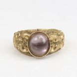 An Antique gold plated pink stone set ring, chased foliate shoulders with oval cabochon foil-back