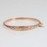 An early 20th century 9ct rose gold hinged bangle/bracelet, engraved floral and foliate