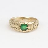 An Antique unmarked high carat gold green stone set ring, ornate engraved shoulders and shank,