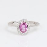 A modern 14ct white gold pink sapphire and diamond cluster ring, set with oval mixed-cut sapphire