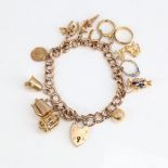 A 9ct gold curb link heart padlock charm bracelet with 11 9ct charms and 1 18ct charm, bracelet