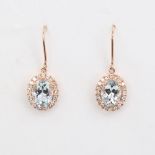 A modern pair of 14ct rose gold aquamarine and diamond cluster pendant earrings, set with oval-cut