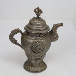 An Indian unmarked white metal teapot, relief embossed decoration with dorje finial, height 17cm,