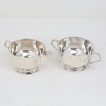 An Art Deco silver matching cream jug and sugar bowl, circular form with geometric handles, by