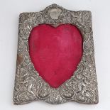 An Edwardian silver-fronted heart-shaped photo frame, relief embossed cherub and foliate decoration,