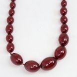 A long graduate single-strand cherry amber bead necklace, beads measuring from 31.4mm to 12.2mm,