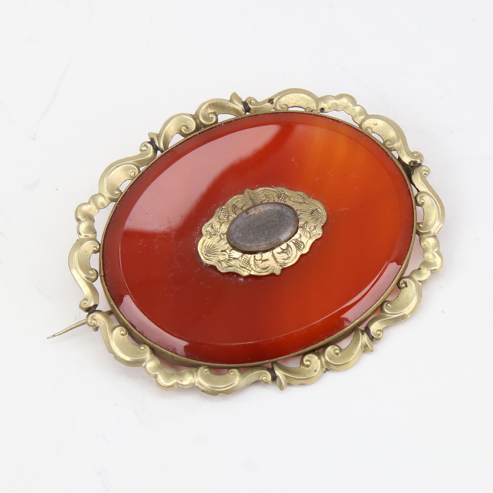 A large Victorian oval mourning brooch, unmarked yellow metal settings with red banded agate and