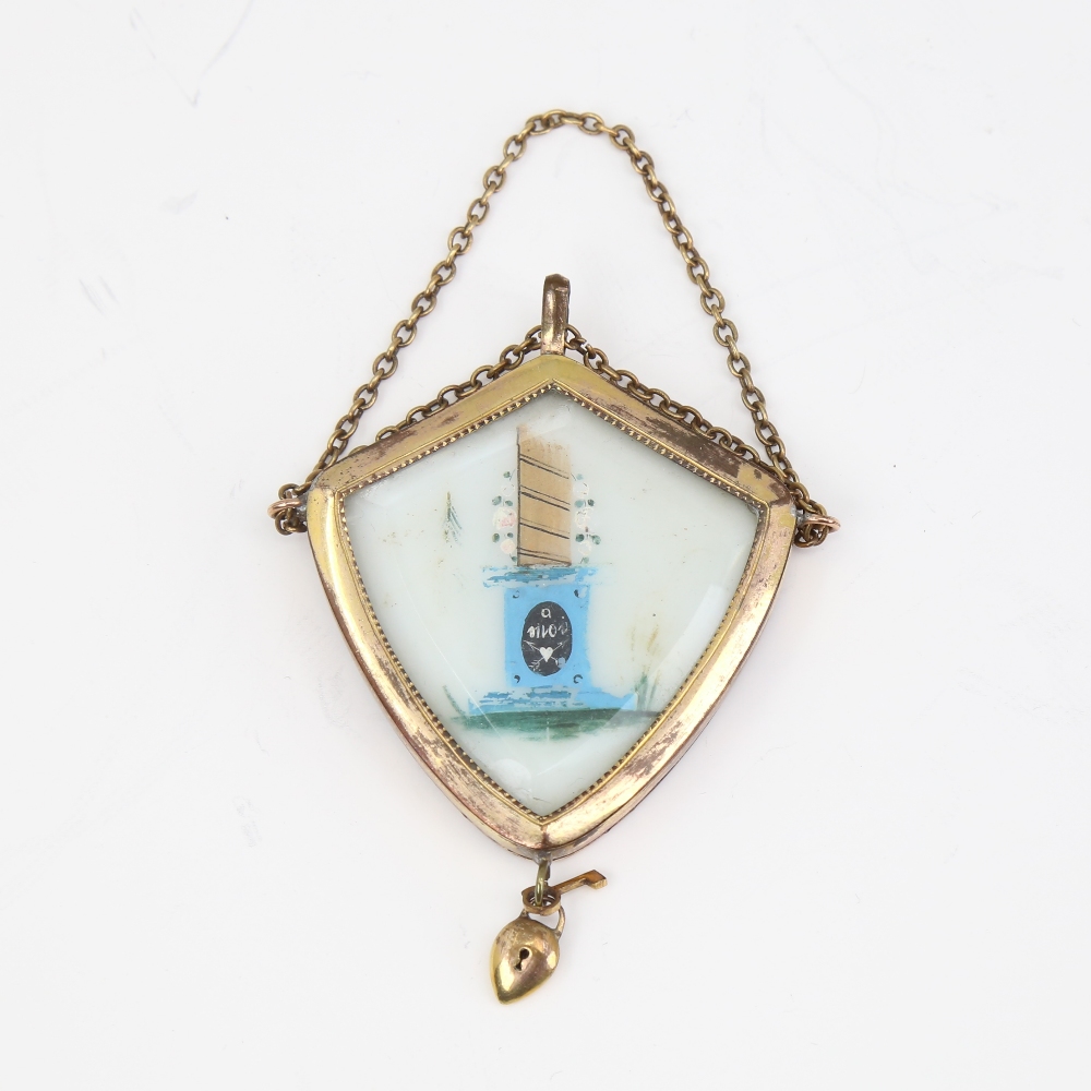 A Victorian unmarked yellow metal mourning pendant, shield form with bevel-glass panels and