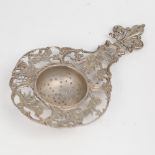 A late 19th/early 20th century German silver tea strainer, relief embossed and pierced decoration