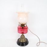 A brass Duplex oil lamp converted to electric, with cranberry glass font, frilled opaque glass shade