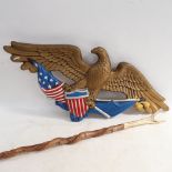 A painted and gilded metal wall plaque, with eagle and flag design, 67cm across, and a horn-