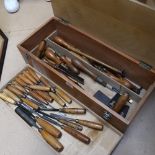 A carpenter's toolbox, containing draw knife, hand saws, and a tray of woodworking chisels