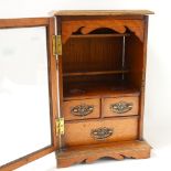 An oak table-top smoker's cabinet, with bevel-glass door and drawer-fitted interior, height 43.5cm