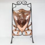 An Art Nouveau wrought-iron and copper shield firescreen, relief embossed floral decoration,