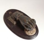 A 19th century cast-iron figural hand and ball door knocker, on a stained mahogany plaque, plaque