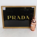 A copper penguin figure cocktail shaker, 23cm, and a Prada advertising sign