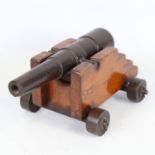 A Georgian patinated bronze table cannon, barrel length 27cm, on original stained wood and bronze