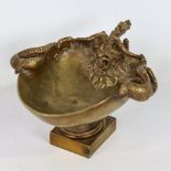 A polished bronze bowl on stand, relief cast serpent and mask designs, length 18cm