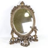 An ornate relief cast-brass framed toilet mirror, on scroll stand surmounted by putti, height 57cm