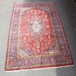 A large red ground Kashan wool rug, floral decoration with border, 298cm x 200cm There is some
