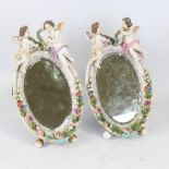 A pair of Continental porcelain framed dressing table mirrors, surmounted by cherub figures, crossed