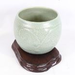 A Chinese celadon crackle glaze jardiniere, height 15cm, overall diameter 19cm, on hardwood stand