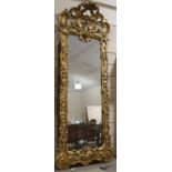 A large relief carved giltwood-framed wall mirror, with elaborate pierced and scrolled pediment,