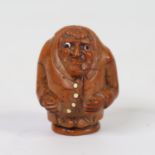An 18th century coquilla nut walking stick handle, in the form of a man with ivory buttoned coat,