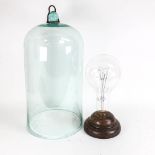 A large glass dome with fitting, height 51cm overall, and an oversized bulb in wooden base.