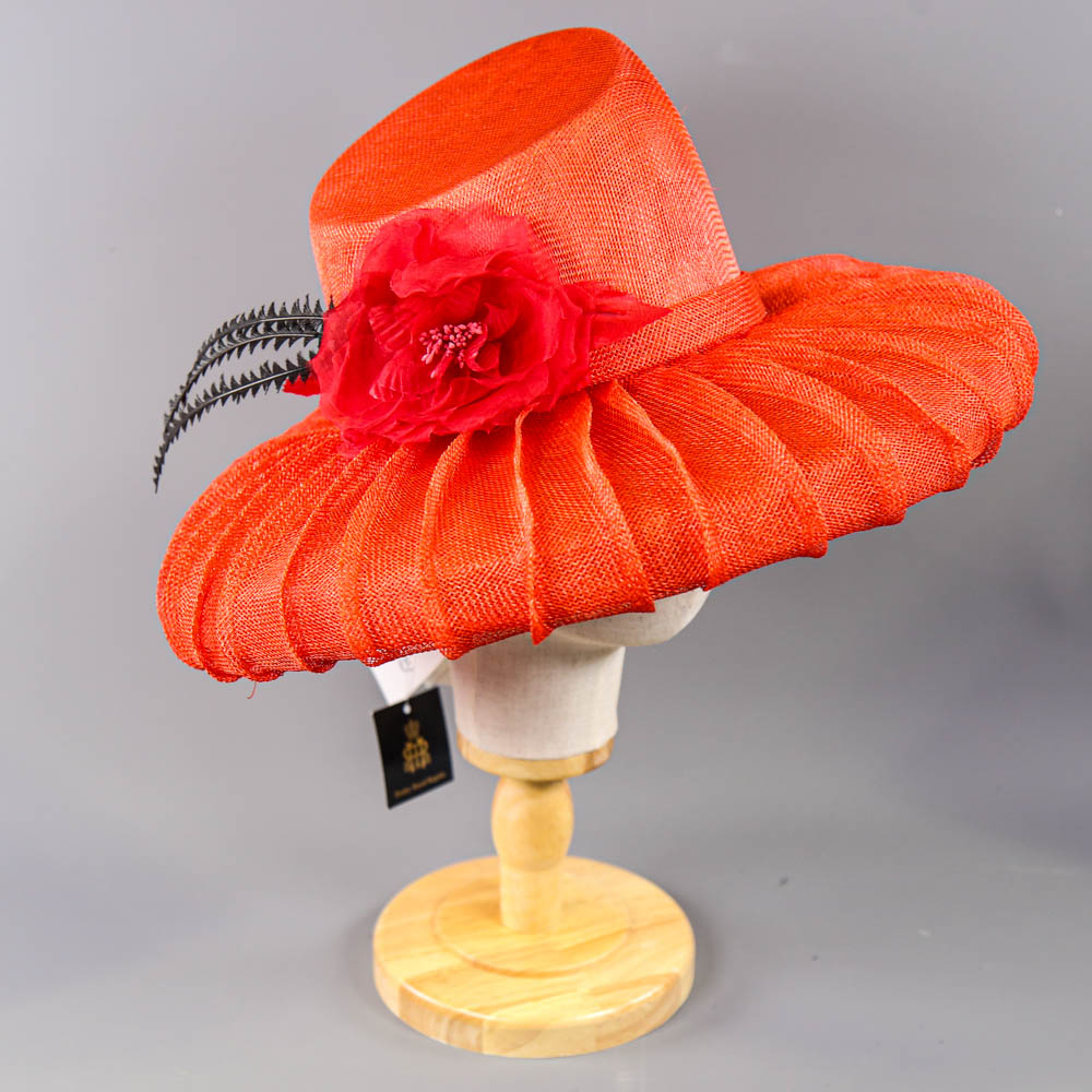 PETER BETTLEY LONDON - Coral red occasion hat, with flower and black feather detail, angled crown,