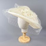 A HAT STUDIO DESIGN - Ivory occasion hat, with net veil and flower detail, internal circumference