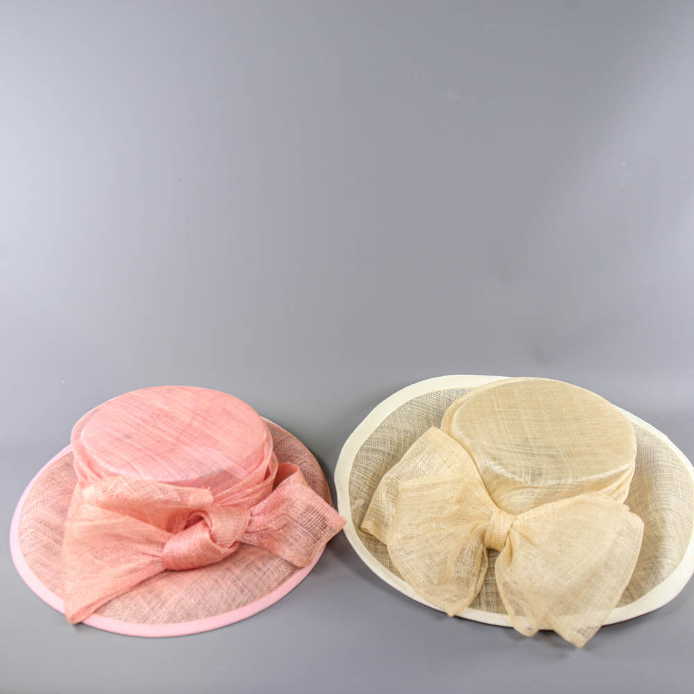 A HAT STUDIO DESIGN - 2 occasion hats, one salmon pink with bow detail, the other champagne with bow