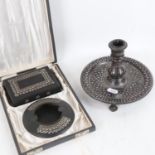A Middle Eastern silver inlaid oxidised metal candlestick, and a similar cased smoker's set (3)