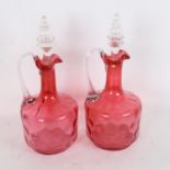 A pair of cranberry glass decanters and stoppers, height 25cm (1 cracked)