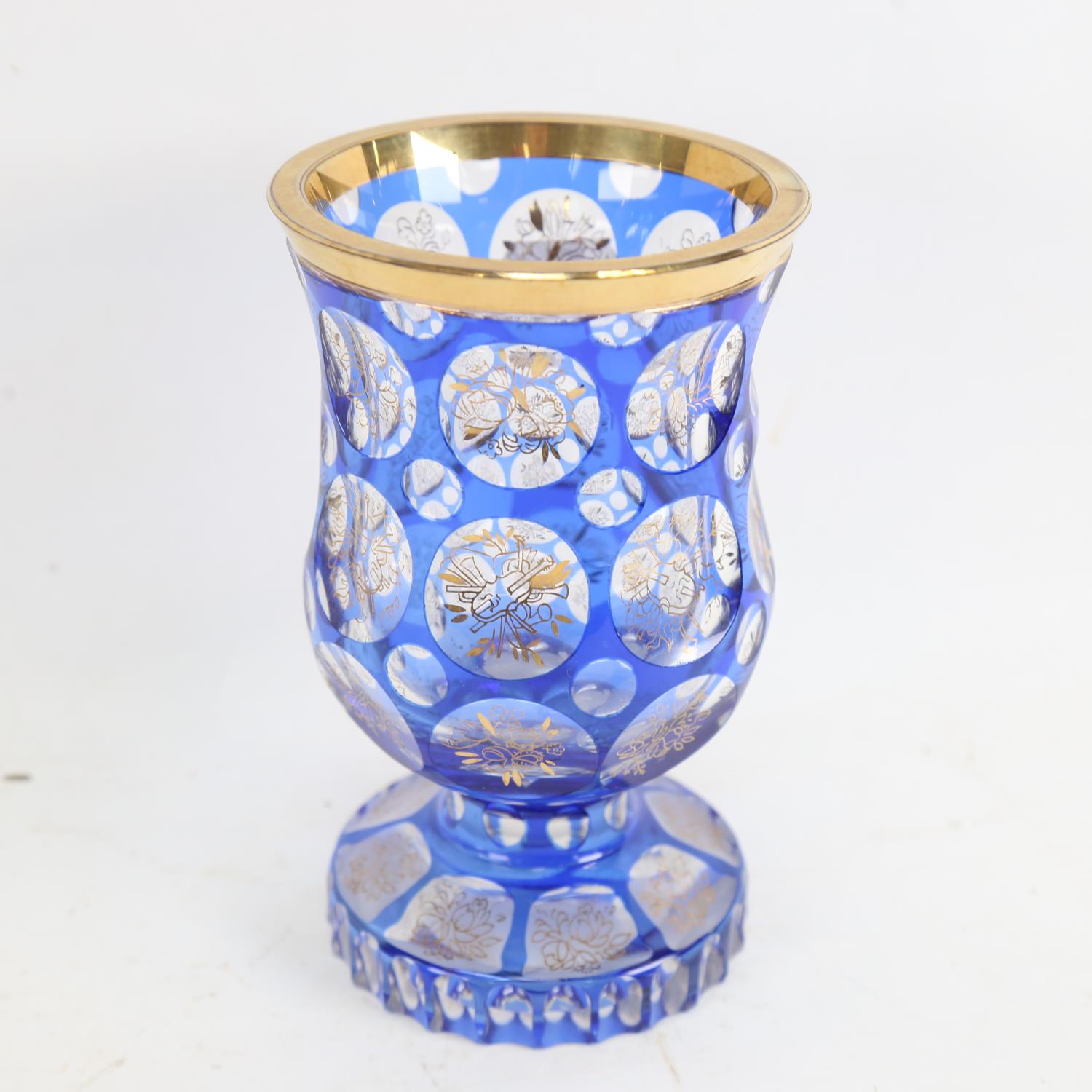 A heavy Bohemian flashed blue overlay glass goblet, gilded instrument and floral decoration, with