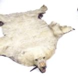 TAXIDERMY - a polar bear skin rug, early 20th century, modelled with head bearing teeth, on felt