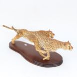 A composition pair of bounding cheetahs, on wooden plinth, by Parker-Hale, length 52cm overall